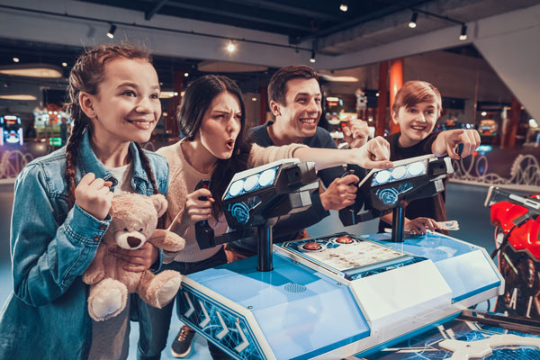Children at an arcade counter holding plush prizes at a family entertainment centre.