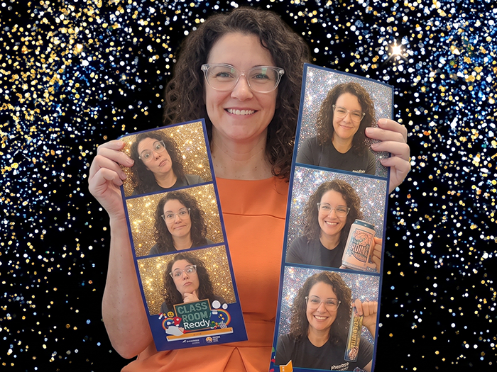 A guest holding two jumbo photo strips printed at an event with Curator, one branded for a school event, against a gold and blue glitter backdrop.